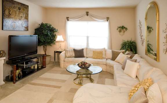 A living room with a white couch, a coffee table, and a television.