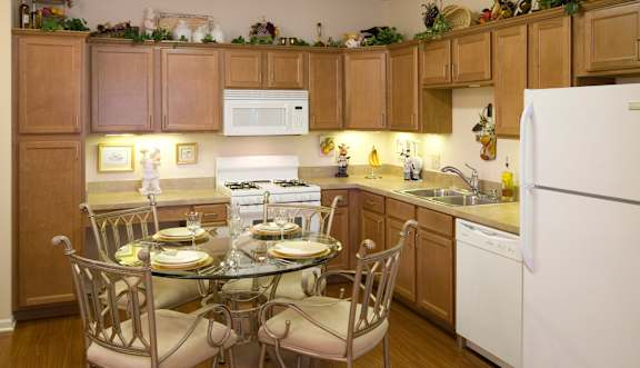 A kitchen with a table set for two and a white refrigerator.