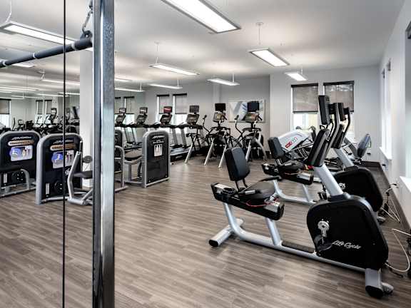 A gym with a variety of equipment including treadmills and weights.