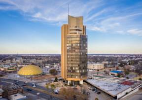 A tall building with a golden dome-like structure in the foreground.