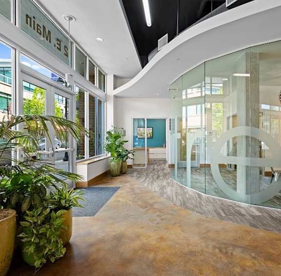 the lobby of a building with plants and glass doors