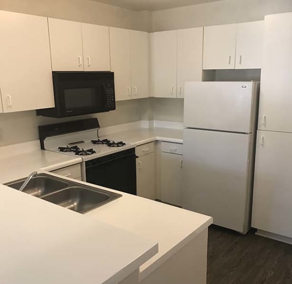 a white kitchen with a sink and a refrigerator at KLIMPEL MANOR Apartments, Fullerton, CA