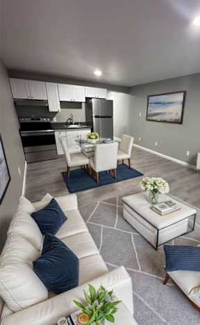 A modern kitchen with white chairs and a wooden floor.