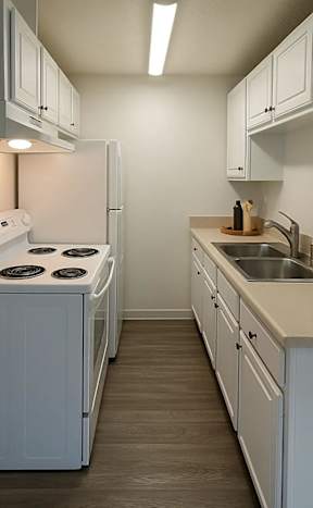 A modern kitchen with white chairs and a wooden floor.