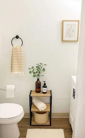 A bathroom with a toilet, a table with a plant and toiletries on it, and a towel hanging on a towel ring.