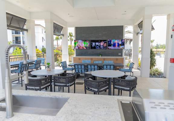 A patio with tables and chairs and a TV on the wall.