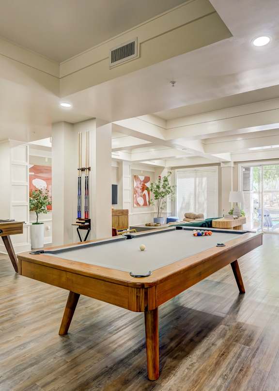 A pool table is in the middle of a room with a lot of windows.