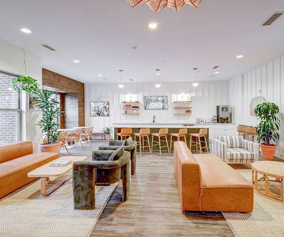 A modern living room with a variety of seating options and a long wooden table at The Linden Apartments, Davidson, NC, 28036