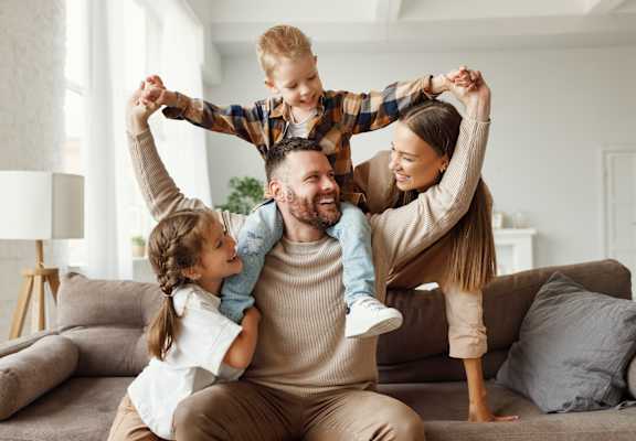 A family of four is having fun on a couch.