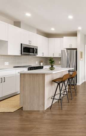A kitchen with white cabinets and a wooden island.