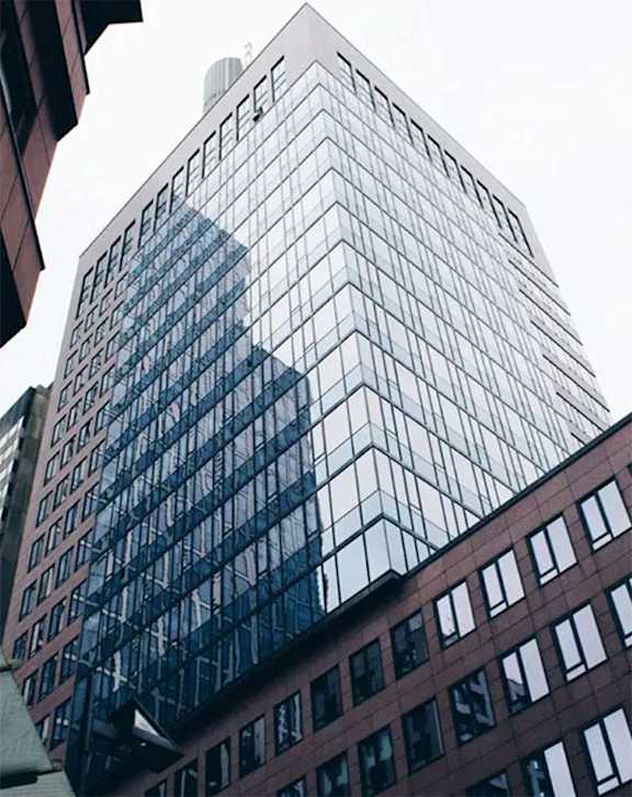 a tall building with a reflection of the sky in it