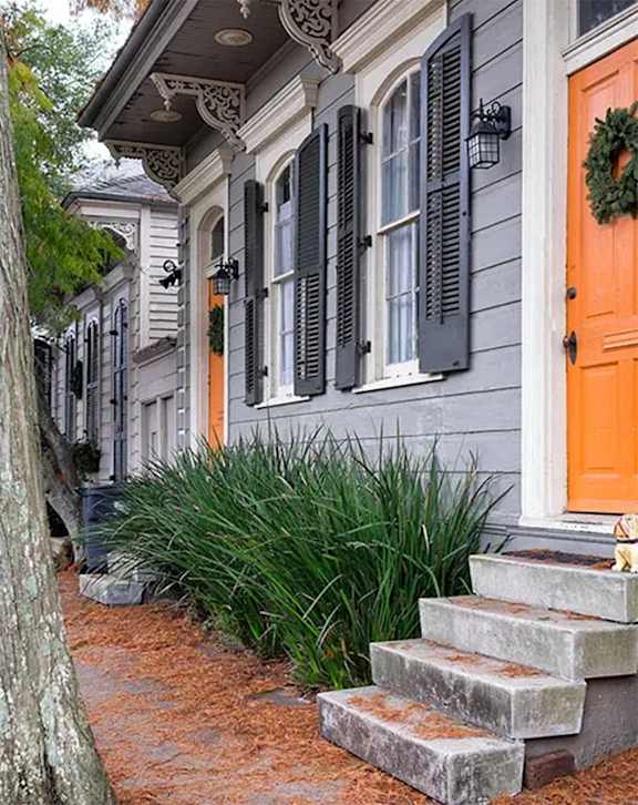 a house with orange door and windows on a sidewalk