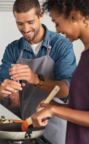 A man and a woman are cooking together in the kitchen.