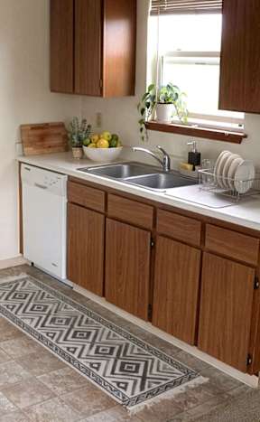 A modern kitchen with white chairs and a wooden floor.