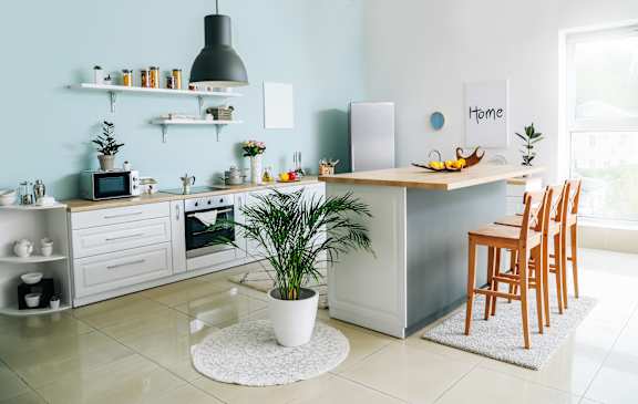 A kitchen with a white countertop and wooden chairs.