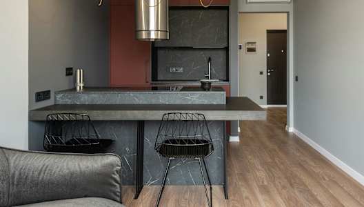 A modern kitchen with a grey countertop and a grey sofa.