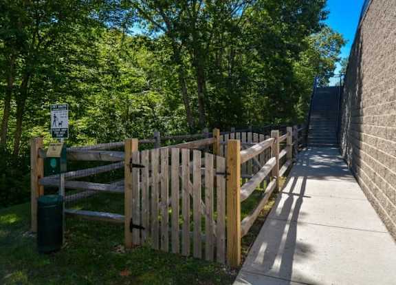 A wooden fence and gate lead to a pathway in a park.