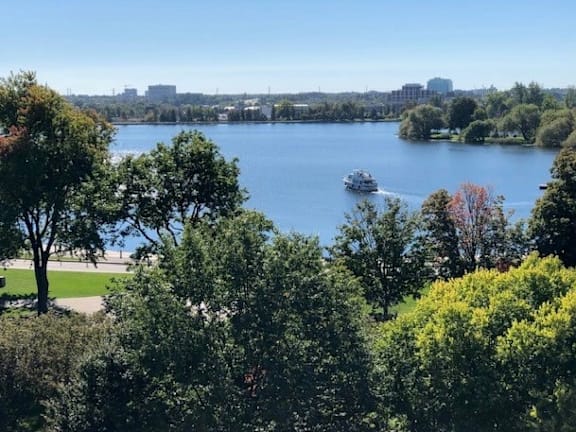 A serene lake surrounded by lush greenery and a boat gently floating on the water.