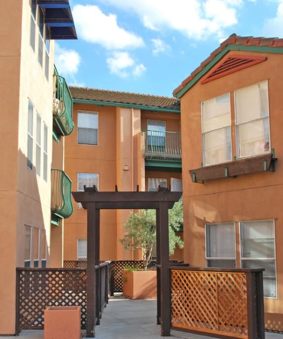 a walkway between two buildings with a blue sky in the background
