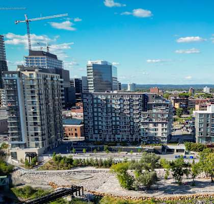 A cityscape with a mix of modern and older buildings, a construction crane, and a clear sky.