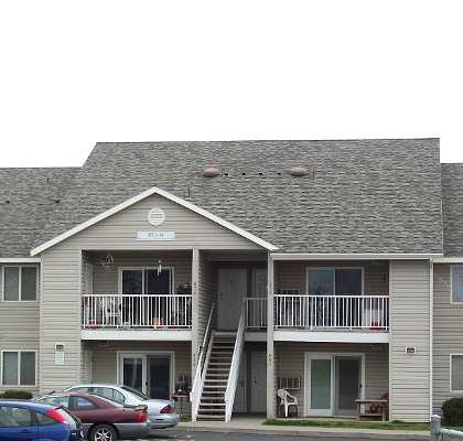 A two story apartment building with a car parked in front.