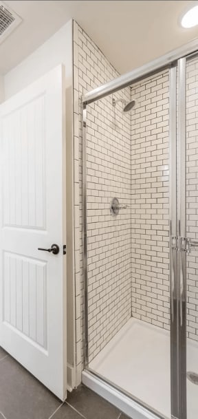 a bathroom with a white door and a shower with a glass door