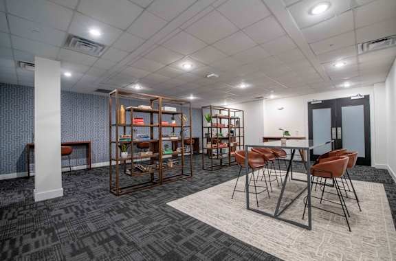 A room with a table surrounded by chairs and a bookshelf.
