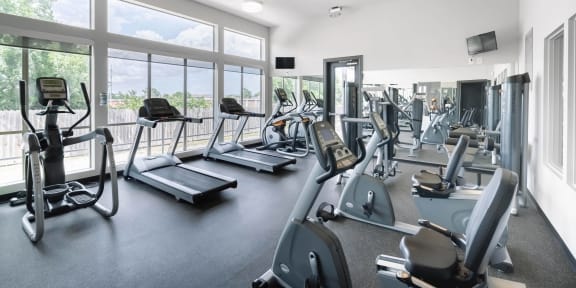 the gym with cardio equipment and windows at the belgard apartments