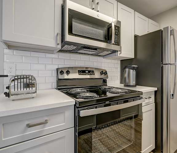 a kitchen with white cabinets and stainless steel appliances and a refrigerator