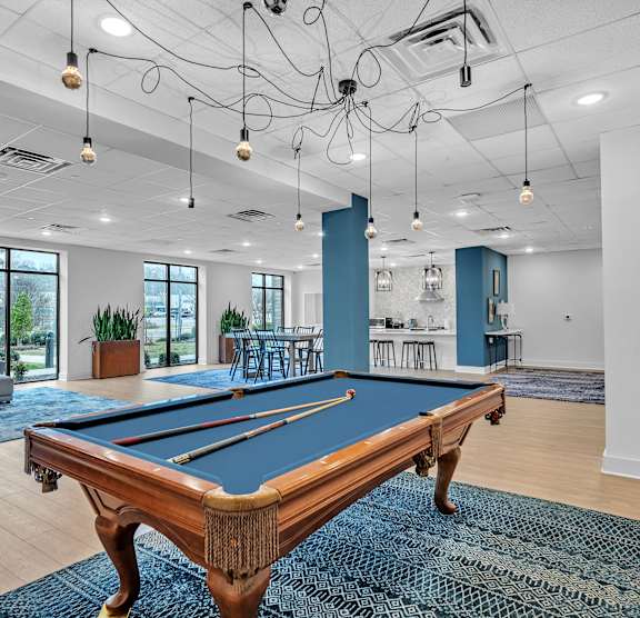 A pool table is in the middle of a room with a blue rug.