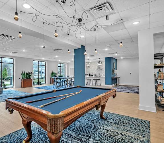 A pool table is in the middle of a room with a blue rug.