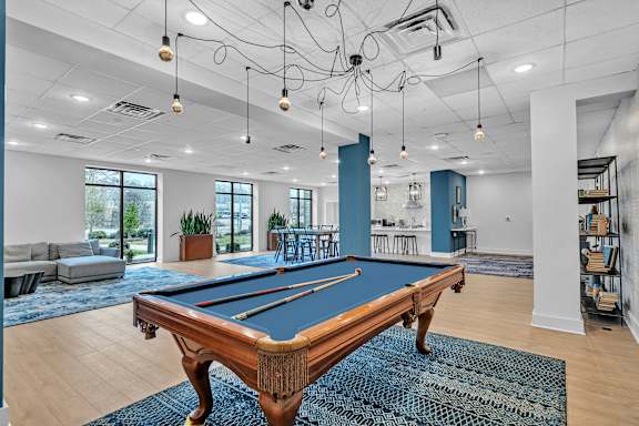 A pool table is in the middle of a room with a blue rug.