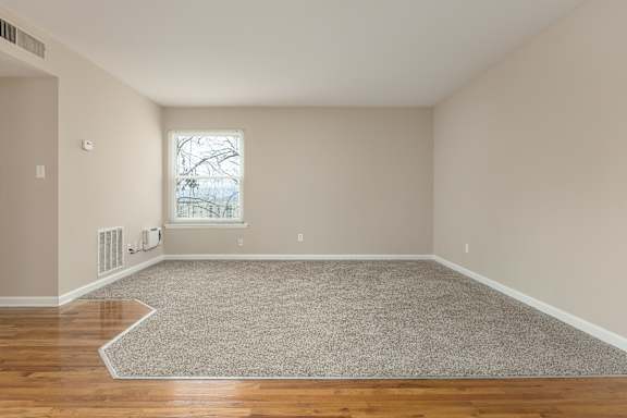 A room with a grey carpet and wooden floor.