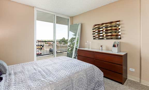 a bedroom with a large window and a bed and a dresser