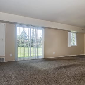 an empty living room with carpet and a large window