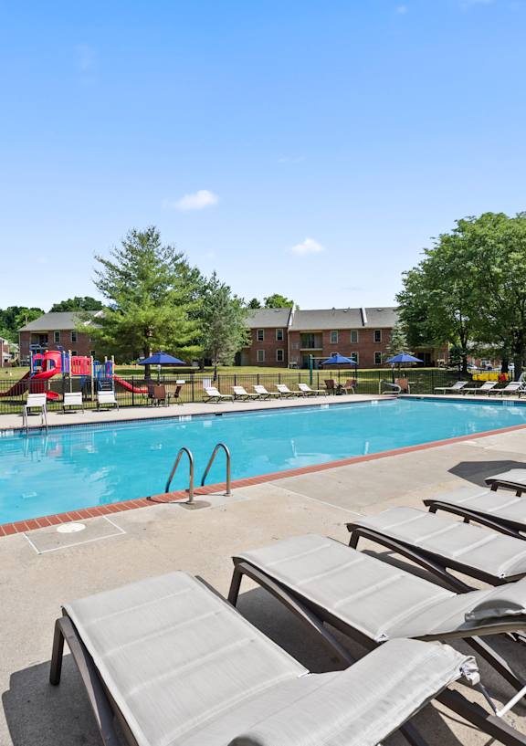 A pool with sun loungers and umbrellas in the foreground.