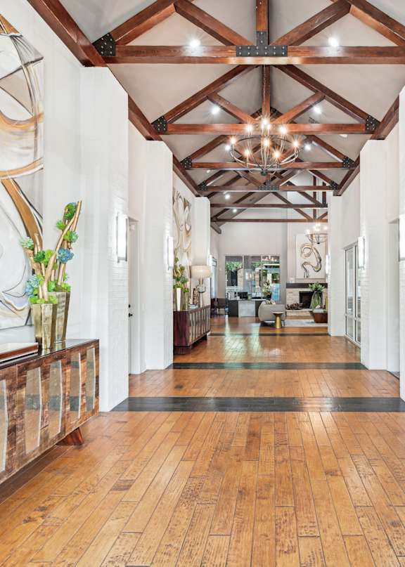 A long hallway with wood floors and a chandelier.