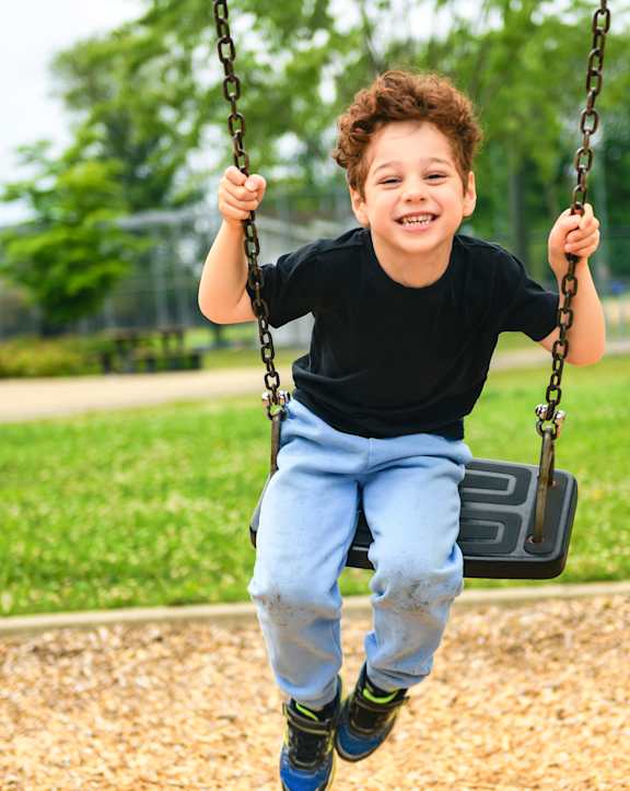 A young boy is swinging on a swing in a park.