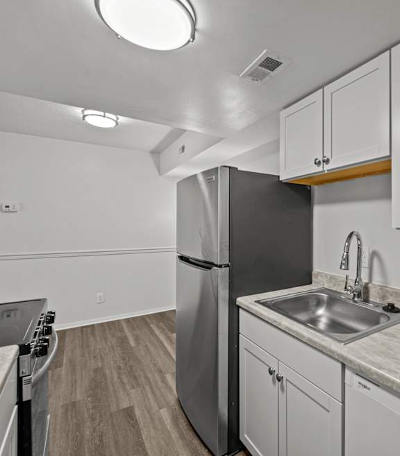 A kitchen with a stainless steel refrigerator and white cabinets.
