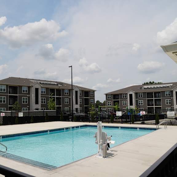 A swimming pool with a diving board and a building in the background.