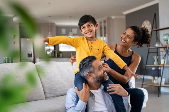 a man and woman with a young boy on their shoulders in a living room