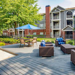 A patio with a blue umbrella and chairs. at Lincoln at Wolfchase Apartments, Cordova, 38016