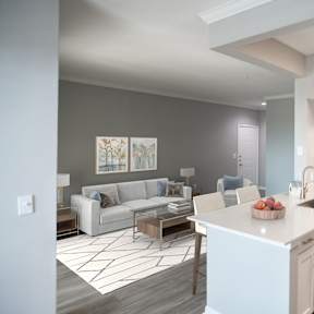 A modern kitchen with a white island and a dining area with a grey sofa.