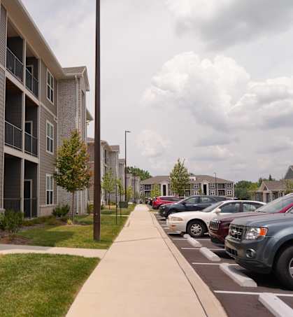 A parking lot with cars parked in front of apartment buildings.