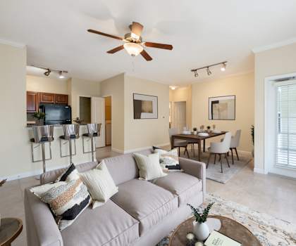 A living room with a grey couch and a ceiling fan.