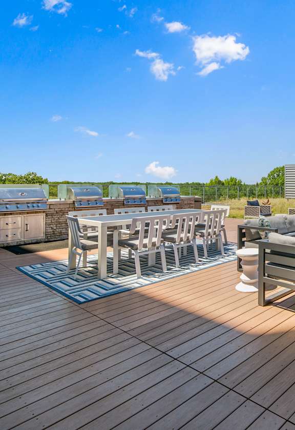 A wooden deck with a table and chairs overlooking a field.