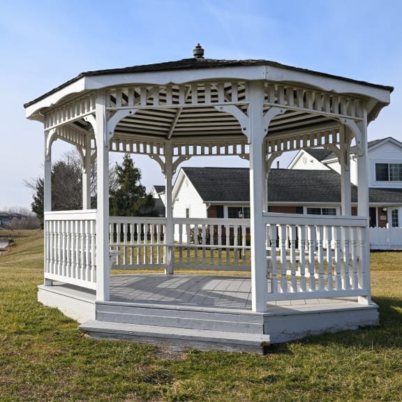 a white gazebo with a river and houses in the background