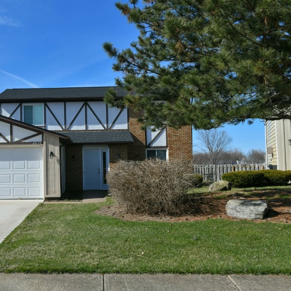 the front of a house with a white garage door and a lawn