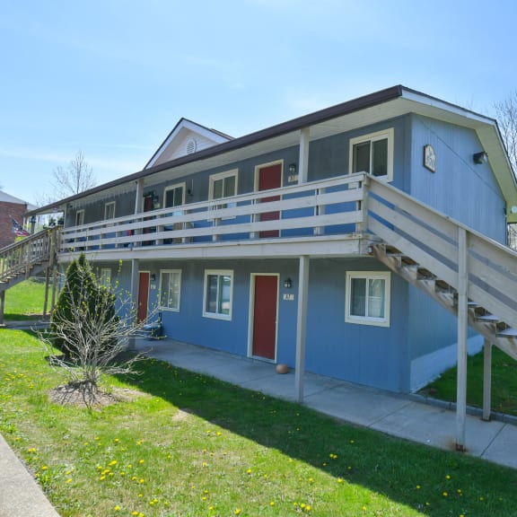 the front of a blue house with a deck and stairs
