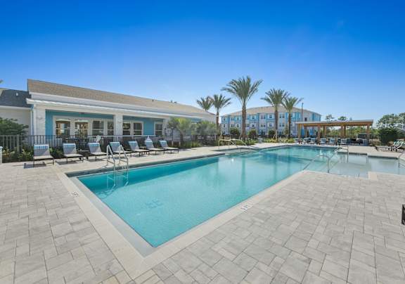 A swimming pool surrounded by a tiled patio and lounge chairs.at Allegra at Cocoa in Cocoa, FL, 32926